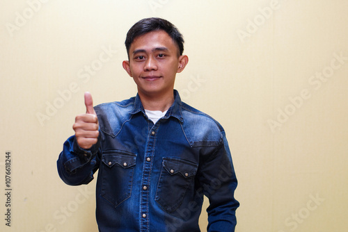 Young caucasian smiling happy attractive positive man show thumbs up like gesture isolated on yellow background studio portrait People lifestyle concept
 photo