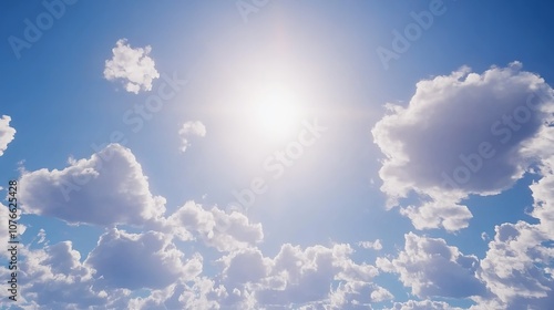 Bright sun shining through fluffy clouds on a clear blue sky

 photo