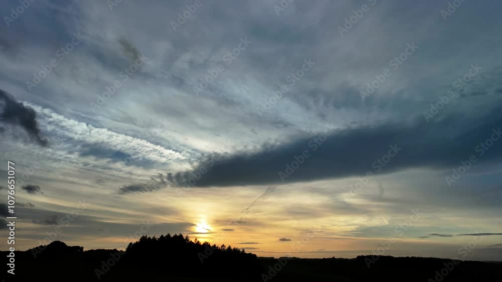 Timelapse of sunset with clouds over a silhouetted area Timelapse of sunset with clouds over a silhouetted area