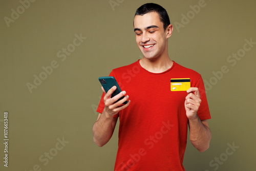 Young middle eastern man he wear red t-shirt casual clothes using mobile cell phone hold credit bank card doing online shopping order delivery booking tour isolated on plain pastel green background. photo