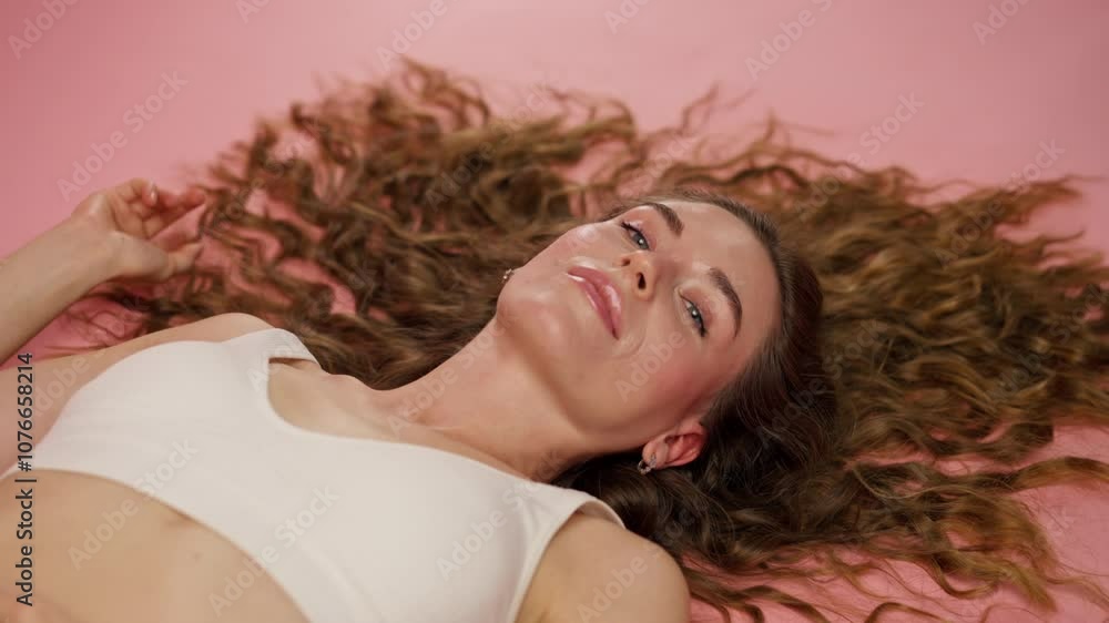 close-up studio beauty shoot on pink background beautiful girl lying in white underwear with loose hair natural beauty close-up studio beauty shoot on pink background beautiful girl lying in white underwear with loose hair natural beauty
