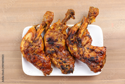 Grilled chicken legs on a white plate, top view food table