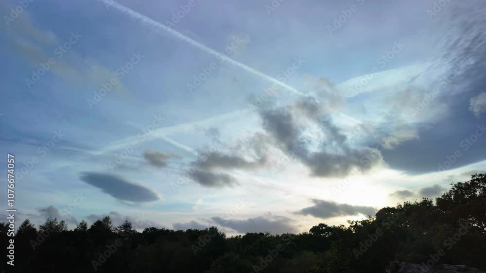 Timelapse of clouds and chemtrails at sunset on a silhouetted forest Timelapse of clouds and chemtrails at sunset on a silhouetted forest