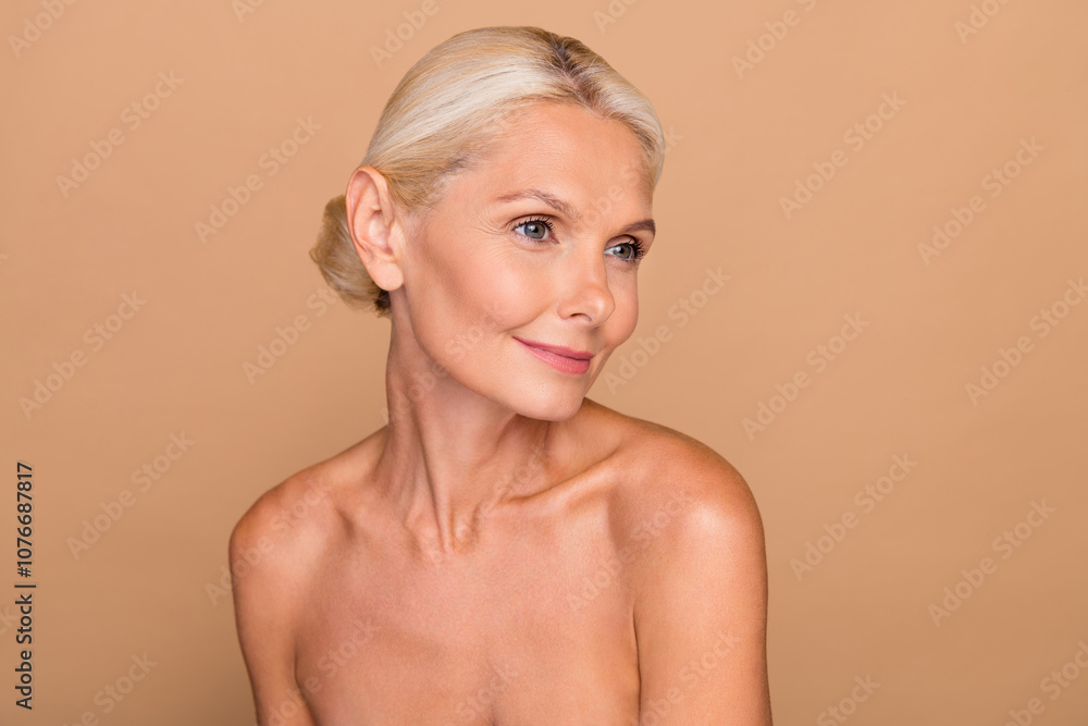 Photo of adorable shiny lady nude shoulders looking empty space smiling isolated beige color background Photo of adorable shiny lady nude shoulders looking empty space smiling isolated beige color background