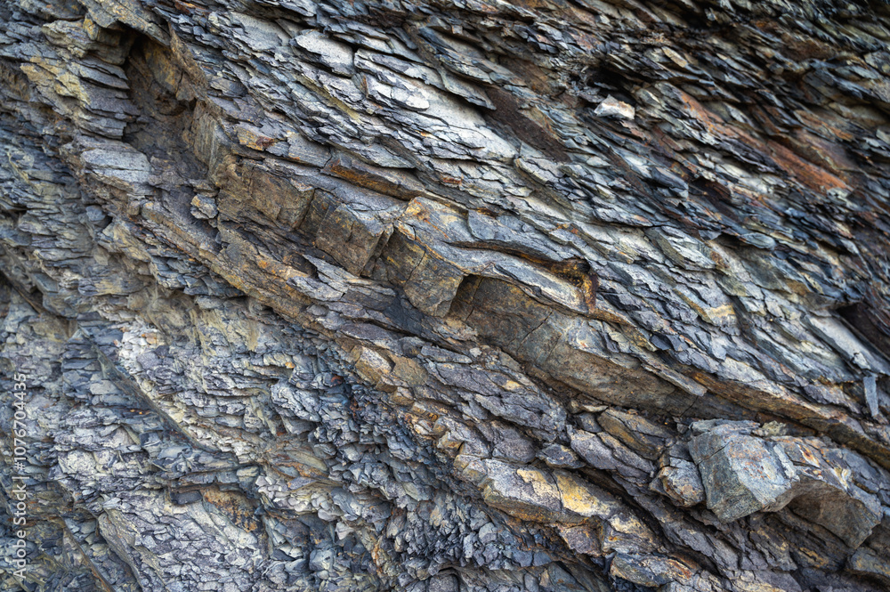 Close-up of layered sedimentary rock formations with diverse textures and natural color tones. Perfect for geology, nature, and abstract backgrounds. Captures rugged, weathered details of ancient ston