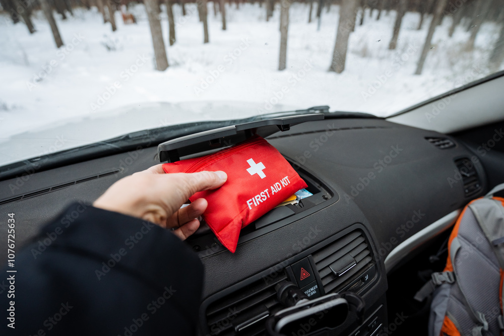 Fototapeta premium In the vehicle, a person is holding onto a first aid kit that is conveniently placed in their car, ensuring they are prepared for any emergency situations that may arise on the road