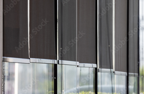 A row of black window blinds with a clear window in the middle photo