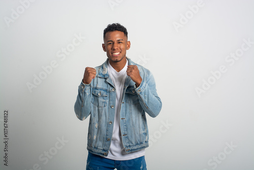 Young handsome African American man wearing casual denim jacket excited for success with arms raised celebrating victory smiling. Winner concept.