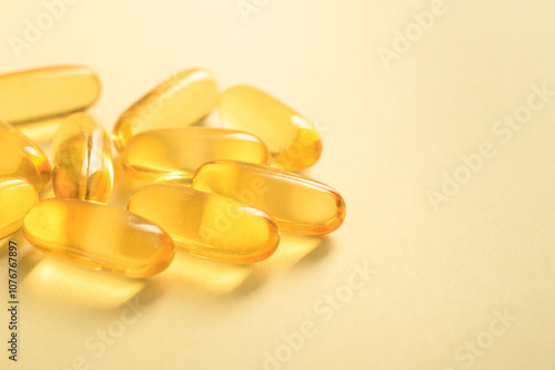 Close up of handful golden color oil fish fat omega-3 in soft gel capsule on yellow background, copy space. photo