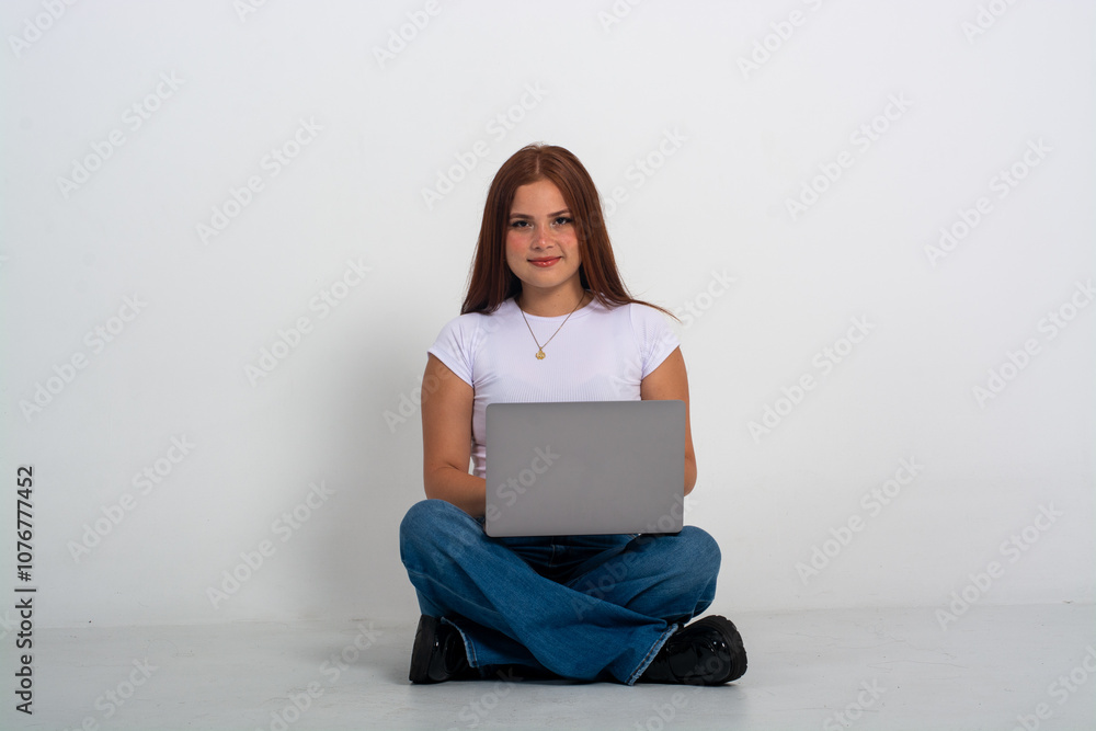 cute woman sitting on the floor with laptop smiling and looking at the camera isolated in a white background cute woman sitting on the floor with laptop smiling and looking at the camera isolated in a white background