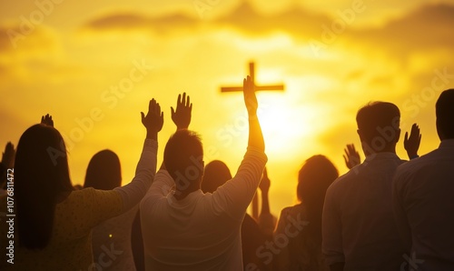 A group of people stand praying at sunset, hands raised in worship, cross in the background
