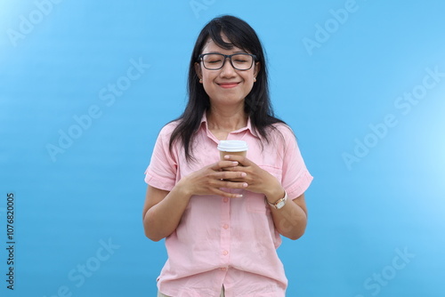 Фотография Portrait of attractive woman smells aromatic coffee, has break, closes eyes with