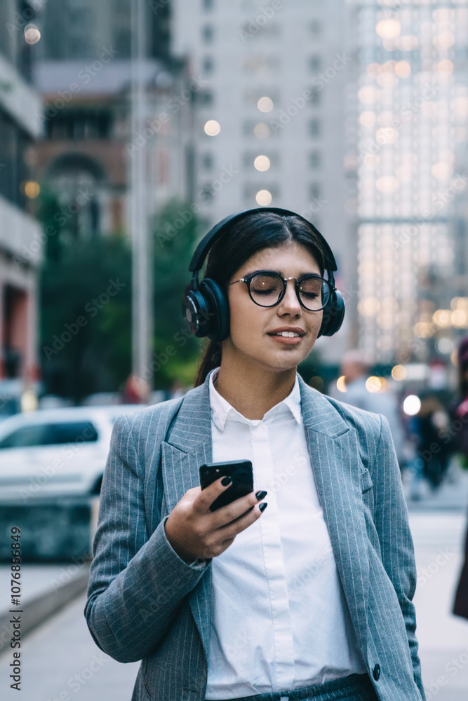 Businesswoman walking in downtown and using smartphone with eyes closed Businesswoman walking in downtown and using smartphone with eyes closed
