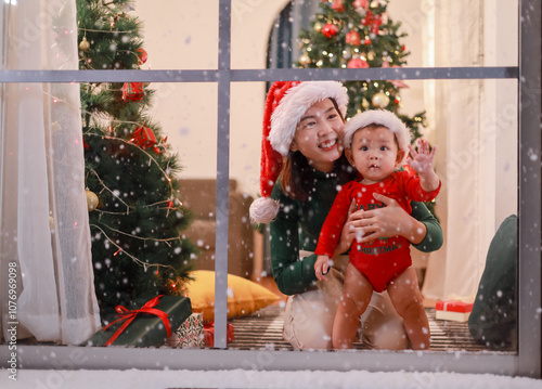 Asian mother and child watching Christmas falling. Happy holiday moment.