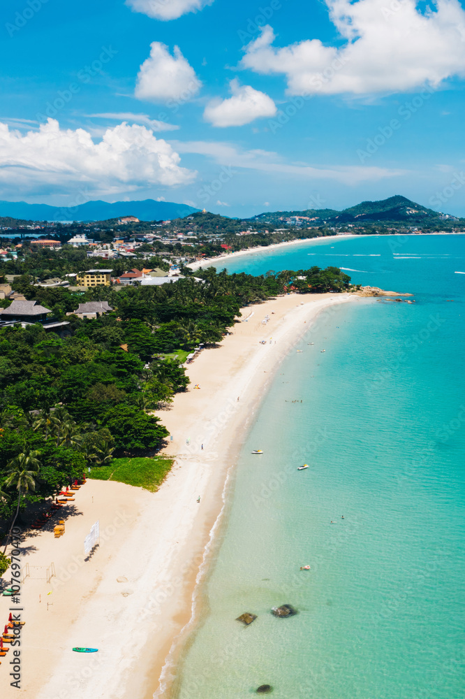 Obraz premium Aerial scenery view of white sand shore with turquoise clear sea water. Bird's eye panoramic view of picturesque lagoon with hotels on beach. Populated island in Thailand. Water Sport Activity