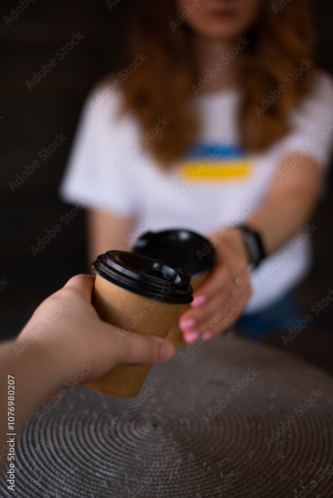 Two hands with cups of coffee in front of a girl in a white T-shirt. Coffee cups Two hands with cups of coffee in front of a girl in a white T-shirt. Coffee cups