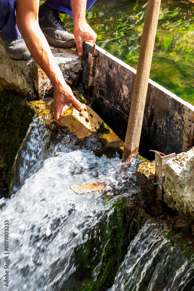 Obraz premium Two hands of a worker repairing and strengthening a dam at Kleptuza Lake in the town of Velingrad, Pazardzhik Province, Southern Bulgaria