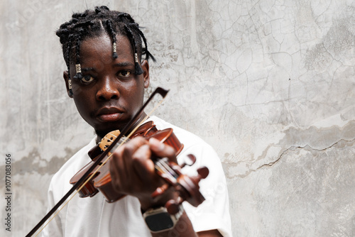 Candid of African man model with dreadlocks hairstyle wearing white t-shirt playing violin standing at the background