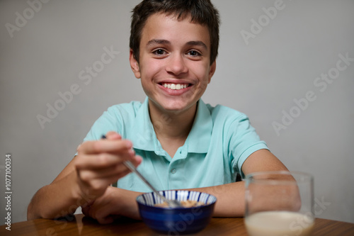 Smiling boy enjoying a healthy breakfast with cereal and milk photo