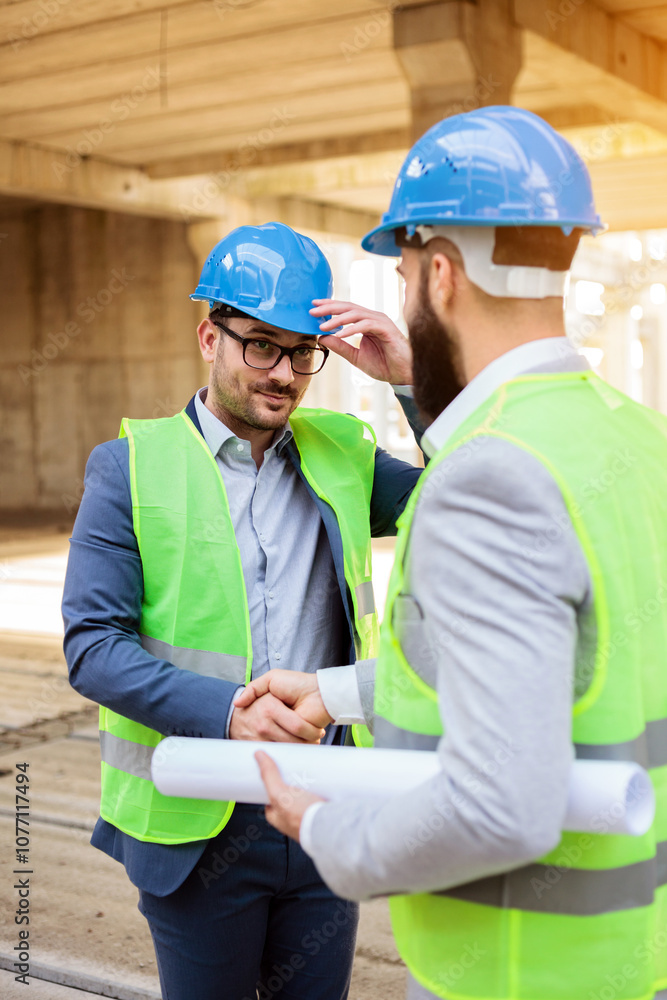 Two young architects shaking hands after a successful meeting on a construction site.