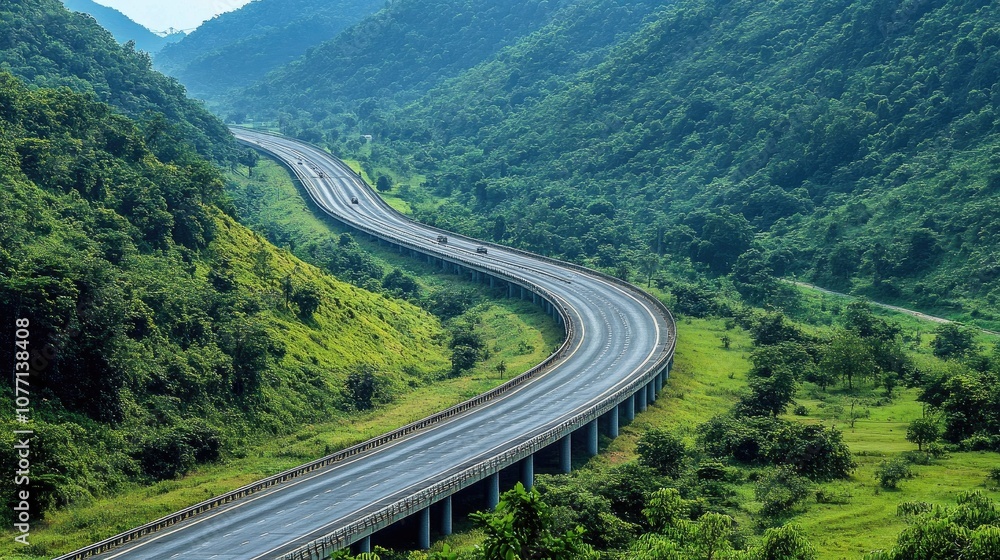 Fototapeta premium Scenic winding road through lush green mountains with a clear blue sky, showcasing beautiful nature and serene landscape in a tranquil outdoor setting