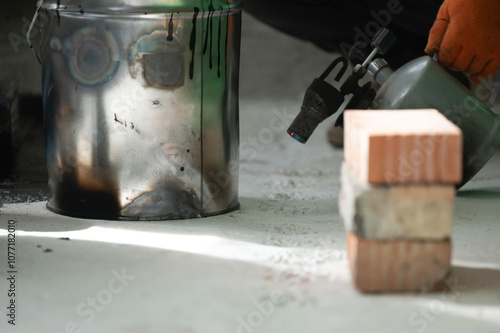 The method of heating resin in a bucket using a kerosene lamp at home. photo