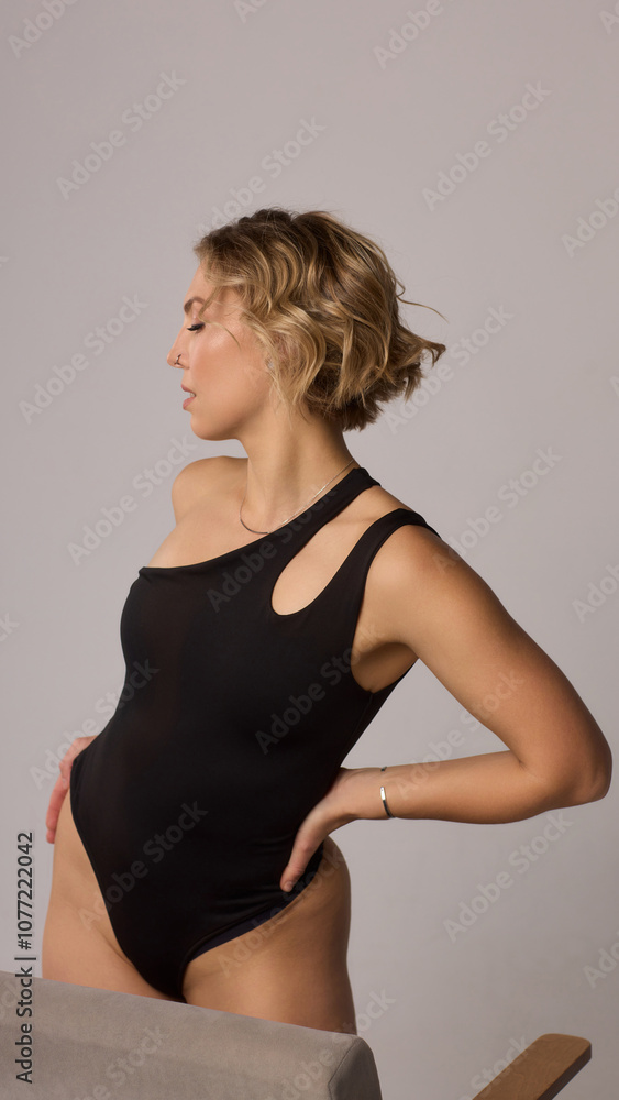 Fototapeta premium Confident Woman with Short Wavy Hair Wearing a Stylish Black Outfit in a Studio Setting
