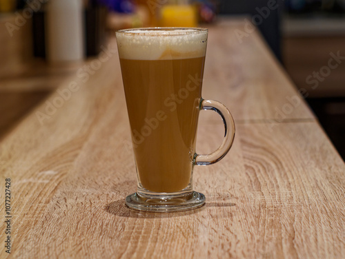 Glass serving of latte on bar