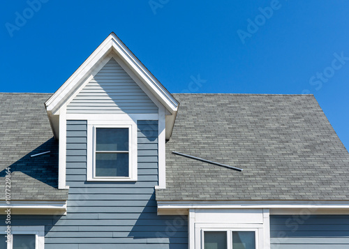Tableau sur toile Gable dormer with blue-gray clapboard siding and white trim on family house in B