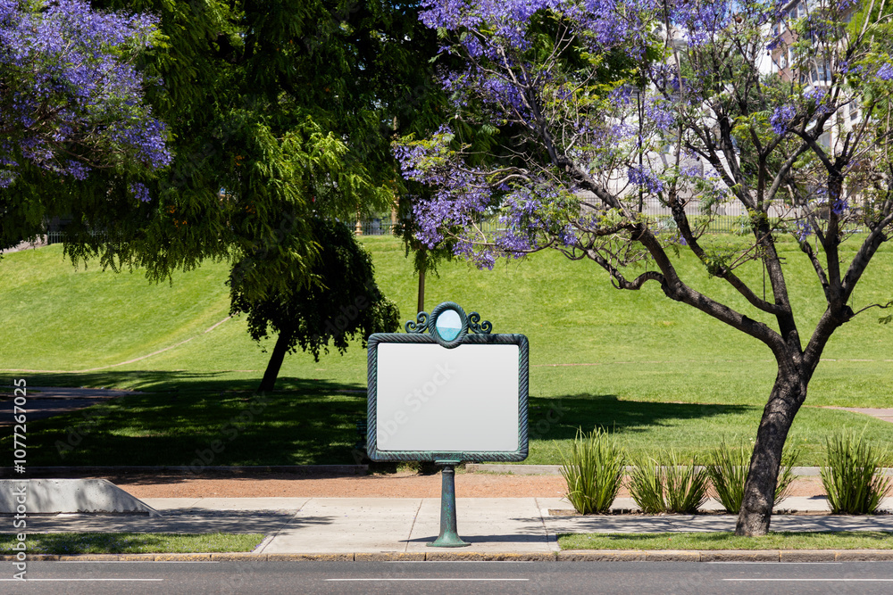 A traditional blank billboard on the street in Buenos Aires, Argentina, with jacaranda trees in the background during spring. Space for advertising signage ideas for mockup