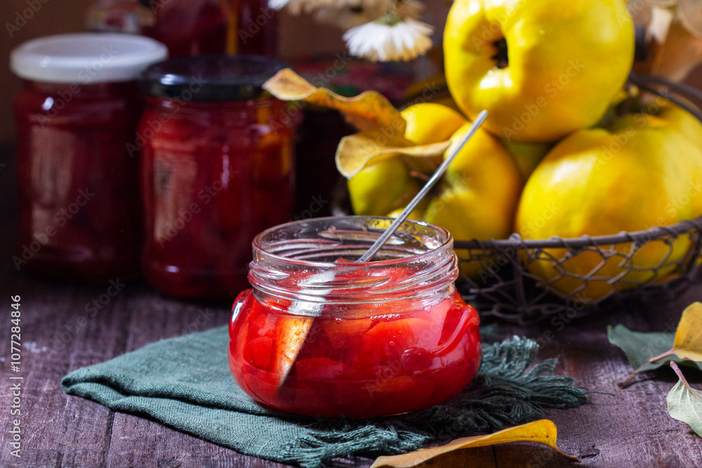 Quince jam in a glass jar, quince in a basket and a bouquet of chrysanthemums. Autumn still life.
