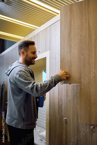 Happy athlete using locker in dressing room at health club. photo