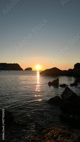 Tropical sunset over the sea, where the sky is tinged with orange and blue, creating a serene landscape.