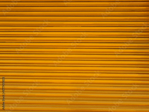 Abstract orange rolling corrugated metal pattern. Background metal corrugated texture in orange brown. Yellow shutter for compositions. Orange metallic texture detailed and seamless wall, grunge.