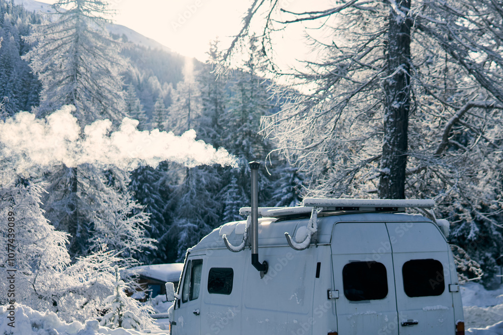 Obraz premium Winter scene with a white van releasing smoke in a snowy forest setting during daylight hours
