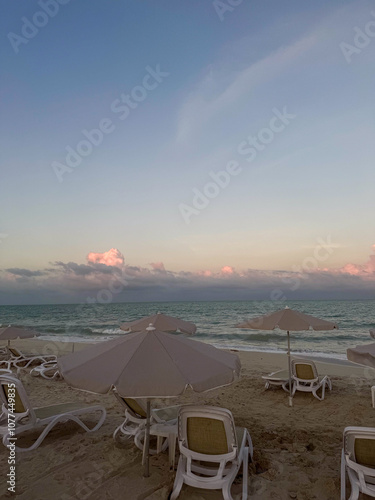 Fototapeta Naklejka Na Ścianę i Meble -  beach chairs and umbrellas on beach at sunset