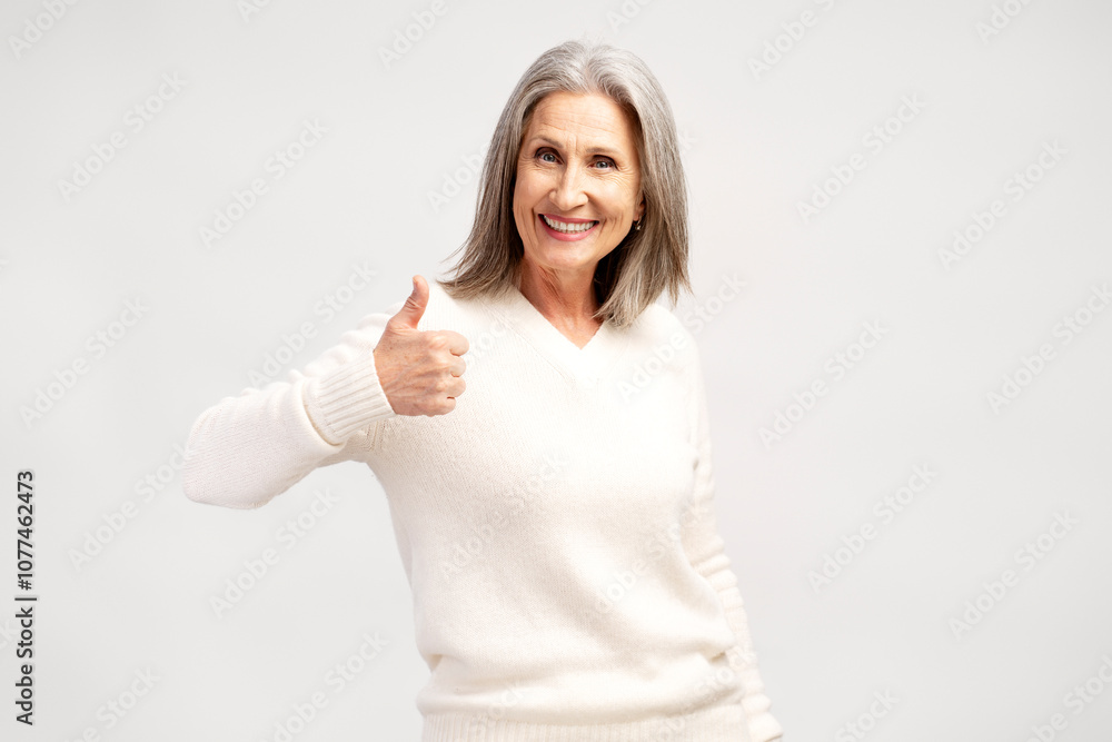 Smiling, positive gray haired woman showing ok gesture thumb up, posing isolated on white background Smiling, positive gray haired woman showing ok gesture thumb up, posing isolated on white background