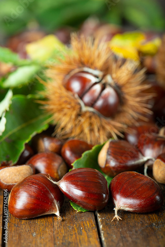 Chestnuts with leaves and burs on a wooden table