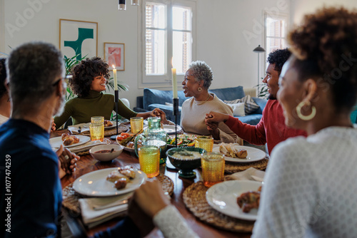 Family holding hands and saying grace before festive meal photo