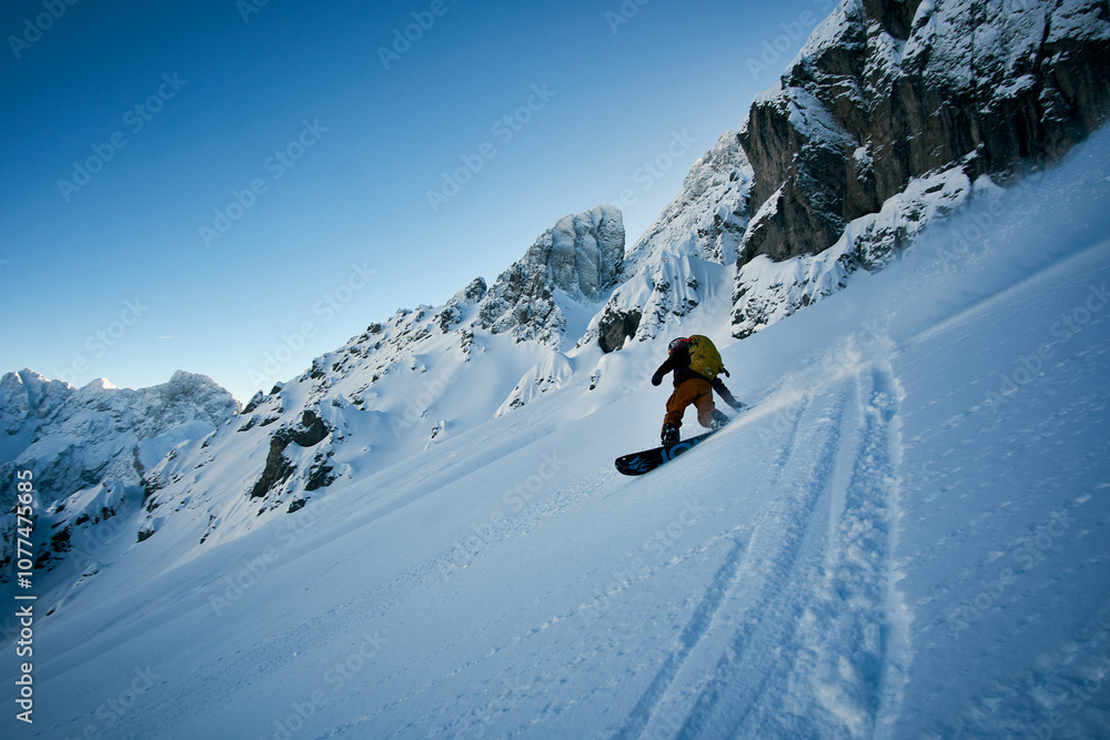 Snowboarder carving through pristine powder on a snowy mountain slope during a clear day Snowboarder carving through pristine powder on a snowy mountain slope during a clear day