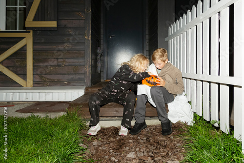 Children inspecting Halloween candy on a porch

 photo