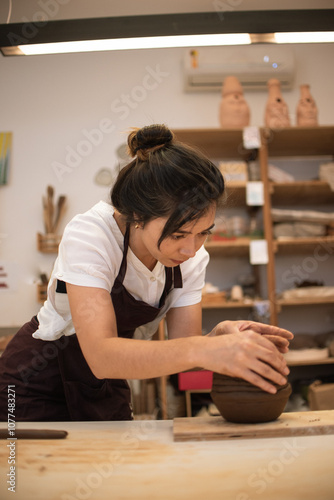 Woman standing, sculpting a clay vase photo