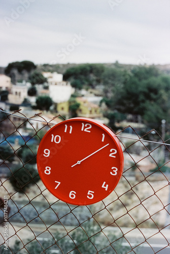 clock at 1:08 hangs from the chain-link fence, 35mm photo