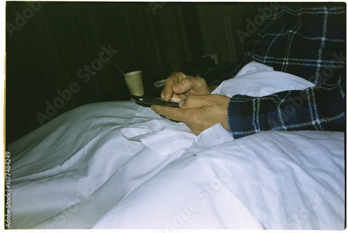 man using his smartphone in bed, 35mm photo