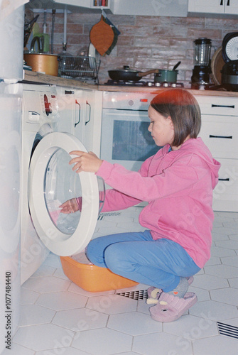 Portrait of girl taking out washed baby clothes at home. photo