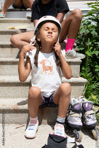 Cute child putting on her helmet before going roller blading photo