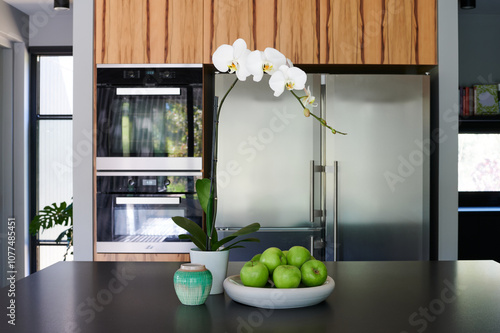 Orchid and green apples on a kitchen counter in a modern home photo