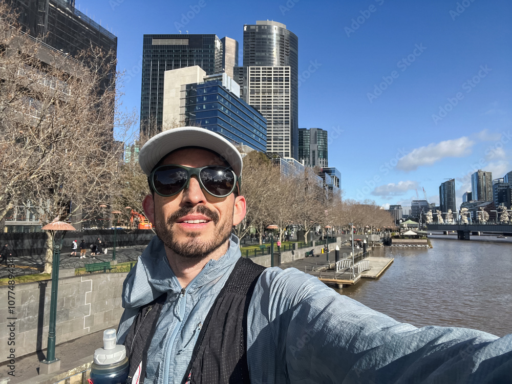Man with sunglasses and cap taking selfie by river in Melbourne Man with sunglasses and cap taking selfie by river in Melbourne