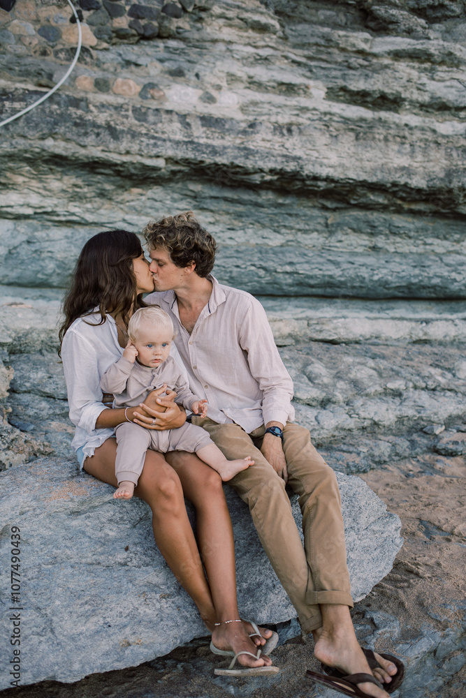 Family sitting on a rock at the beach with baby on lap Family sitting on a rock at the beach with baby on lap