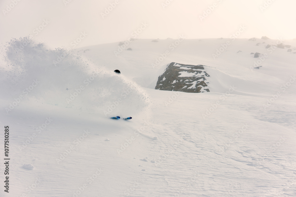 Skiing through fresh powder in a snowy mountain landscape during a cloudy winter day Skiing through fresh powder in a snowy mountain landscape during a cloudy winter day